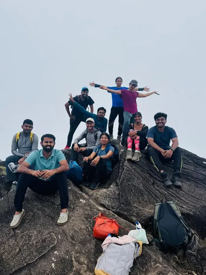 The group posing on a massive rock formation near the summit. The landscape here is rugged and dramatic.