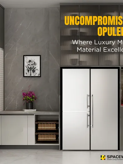 This L-shaped kitchen demonstrates uncompromising opulence through its material choices. The design combines grey marble-textured wall panels, sleek cabinetry, and glass display shelves, all built around a large side-by-side refrigerator.