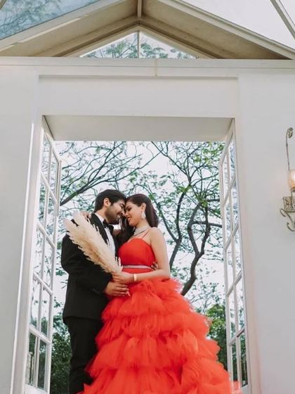 A romantic close-up from a pre-wedding shoot featuring our red ruffled gown. The vibrant color and soft texture of the ruffles create a beautiful frame for the couple.