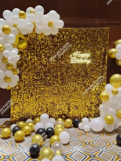 A gold sequin backdrop with a white and gold balloon garland, perfect for elegant parties.