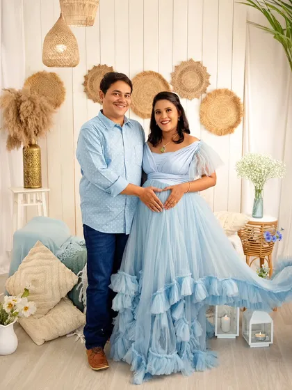 A beautiful couple's portrait in our blue-themed boho studio. They form a heart with their hands on the baby bump, a classic symbol of their love.