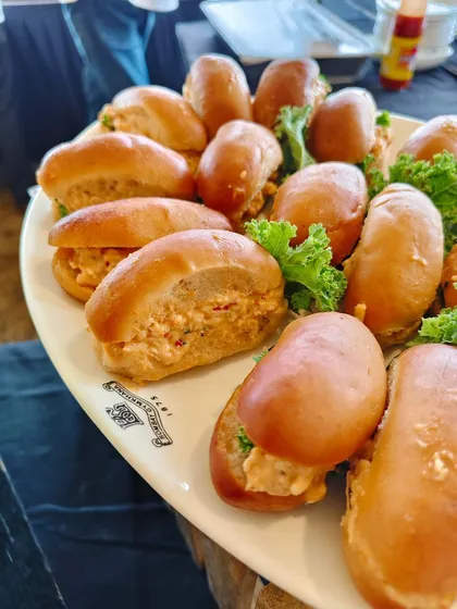 Mini chicken salad sandwiches served on a platter bearing the iconic Bombay Gymkhana logo. We love adding personalized touches to our events.