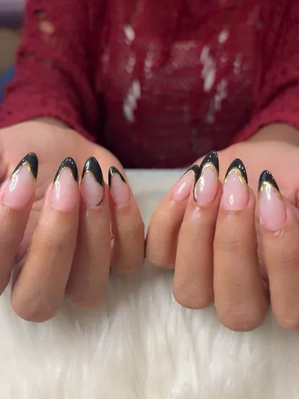 A full view of the V-shaped black French tips with a delicate gold chrome outline.