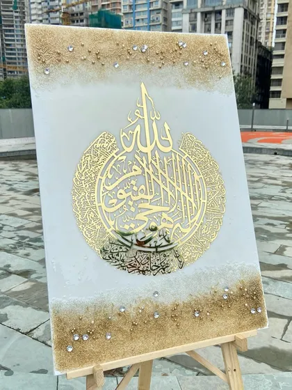This stunning Ayat Ul Kursi resin art piece, set on an easel, embodies peace and protection. It features intricate golden calligraphy on a white and sand-colored background, blending Islamic symbolism with refined luxury.