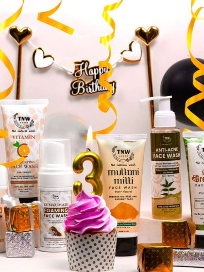 A vibrant and festive shot for a brand's third birthday. The colorful cupcake and party decorations create a fun and energetic atmosphere around the skincare products.