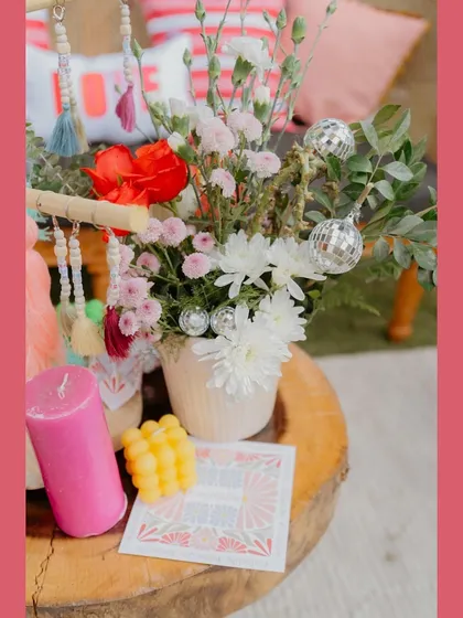 A beautiful flat lay of decor elements, including a custom-printed card, a vibrant candle, and a mini disco ball, all reflecting the event's fun and personal vibe.