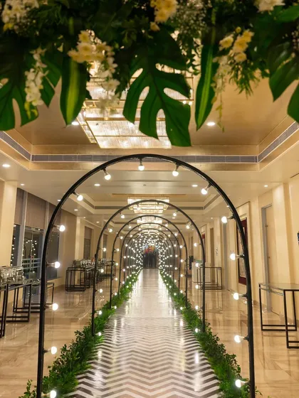 A modern and chic Sangeet entrance. We designed this tunnel of light arches and lush tropical foliage to create a dramatic and glamorous pathway for guests, setting the tone for a night of celebration.
