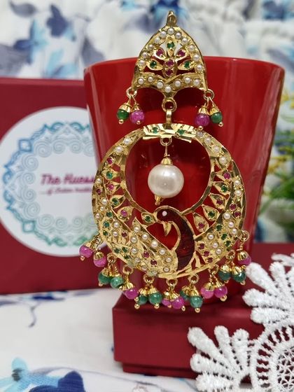 The red peacock 'मोर चंदबाली' showcased in its gift box. These earrings make for a perfect gift, combining artistry with vibrant colours.