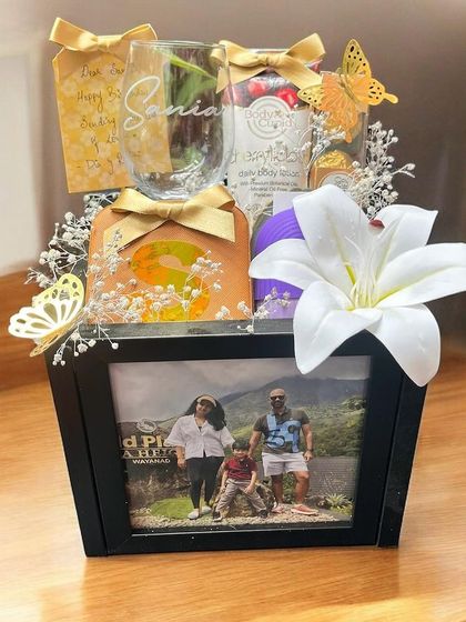 A personalized Rakhi gift centered around a cherished memory. This hamper features a family photo in a black frame, accompanied by a custom-named glass and other treats.