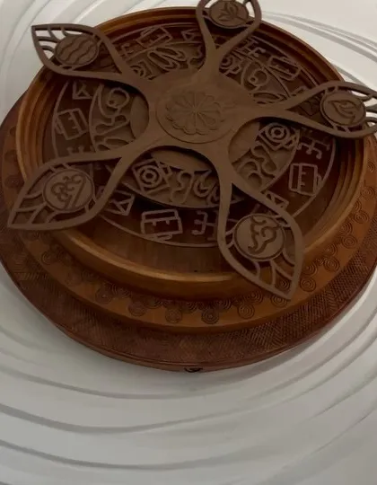 A close up of the custom designed wooden centerpiece for our relief wall project. The intricate patterns and layered design add a focal point of warmth and detailed craftsmanship against the flowing white sculpture.