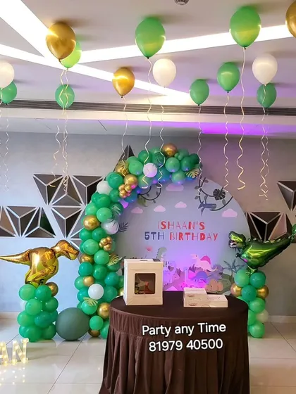 A wide view of the dinosaur party setup, including helium balloons on the ceiling to add to the festive atmosphere.