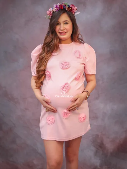 A sweet and feminine look with this lovely pink dress adorned with roses. The floral crown adds a touch of bohemian charm to this maternity portrait, perfect for celebrating a mom-to-be.