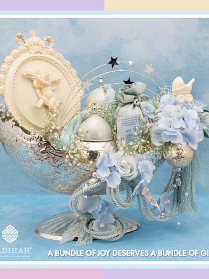 A heavenly baby announcement hamper in a silver-plated bowl. This arrangement for a little boy features soft blue flowers, an angel figurine, and a personalized announcement card, creating a bundle of joy.