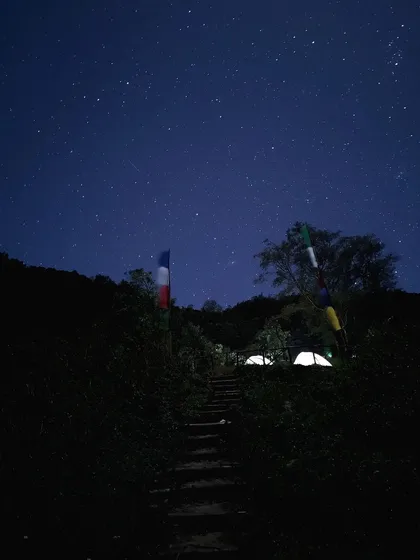 The campsite under a clear, starry night sky, with the tents faintly lit.