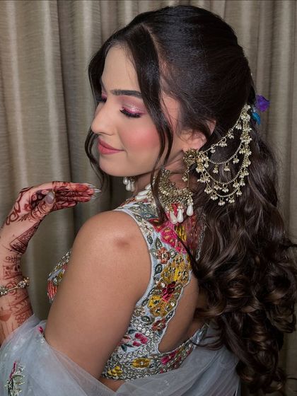 A side profile showcasing her complete Mehendi look. The combination of the floral hairstyle, colorful makeup, and stunning jewelry is just perfect.