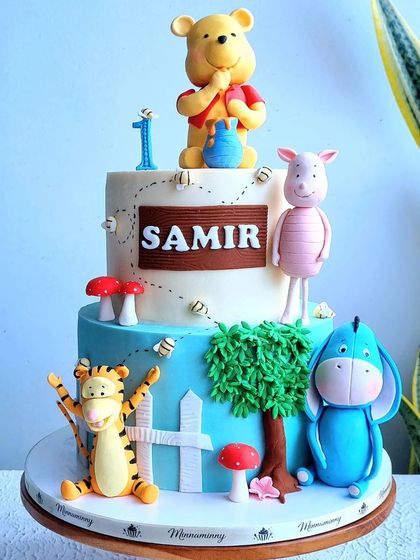 A detailed look at a Winnie the Pooh cake, showing the hand-sculpted characters of Pooh, Piglet, Tigger, and Eeyore.