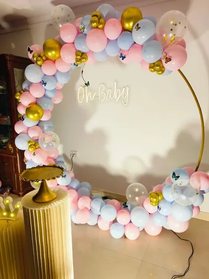 An angled view of the gender reveal balloon ring, showing the cake stand and crown prop.