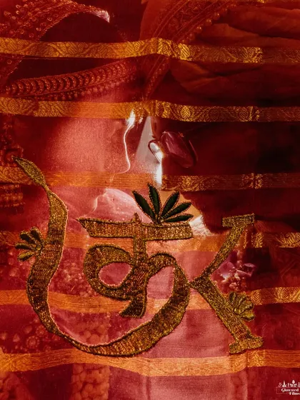 An artistic and creative shot of the bride, Kriti, seen through her red veil which is embroidered with the couple's initials.