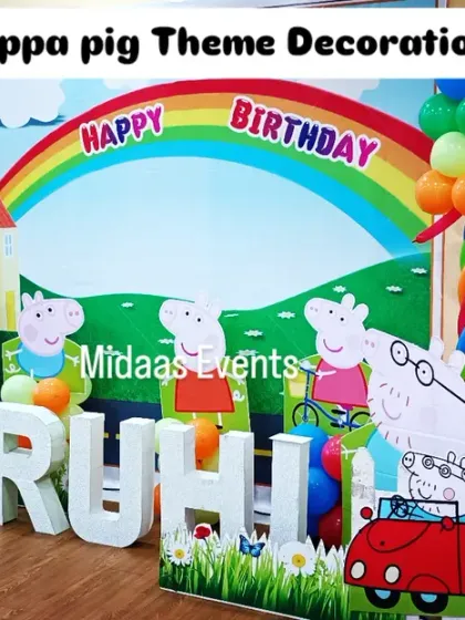 A full view of the Peppa Pig birthday setup. This decoration includes a colorful backdrop, character cutouts of the whole family, and large foam letters spelling the birthday girl's name, RUHI.