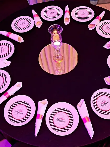 A chic table setting for a ladies' party with custom 'Hello Gorgeous' plates. The black, white, and pink color scheme is modern and stylish.