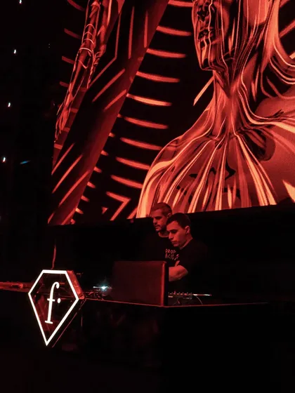 The artists 999999999 at the decks, bathed in the red glow of the club's massive LED screen.