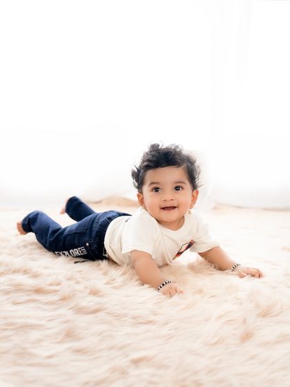 A classic tummy-time pose for the youngest brother. The clean, high-key background keeps the focus on him.