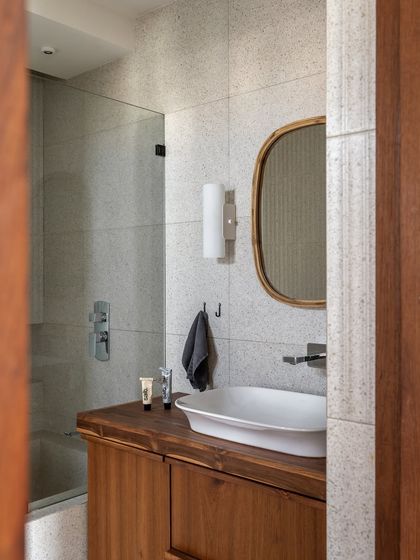 A peek into the master bathroom, where a wooden vanity and simple terrazzo-style tiles continue the home's natural material palette. The design is clean, functional, and filled with warmth.