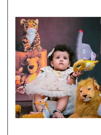 A sweet moment from a jungle-themed baby shoot, where the little one is holding a stuffed animal. The soft lighting and collection of plush toys create a safe and cozy safari environment.