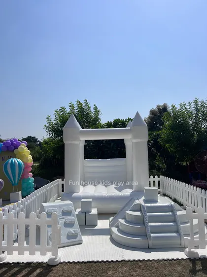Our white soft play area set up outdoors on a sunny day, ready for adventure. The setup includes a mini climbing wall, steps, and a bounce house.