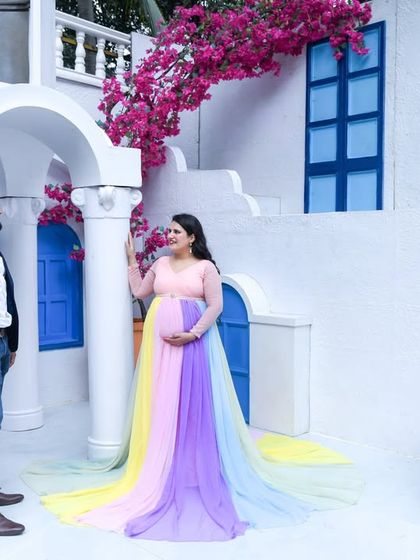 A stunning shot of a couple at a Santorini-themed location. The mom-to-be's rainbow gown provides a beautiful splash of color against the white and blue architecture.