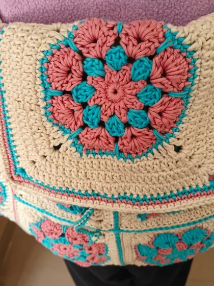 A close-up of the intricate floral granny square pattern on the custom backpack. The combination of pink and turquoise is just beautiful.