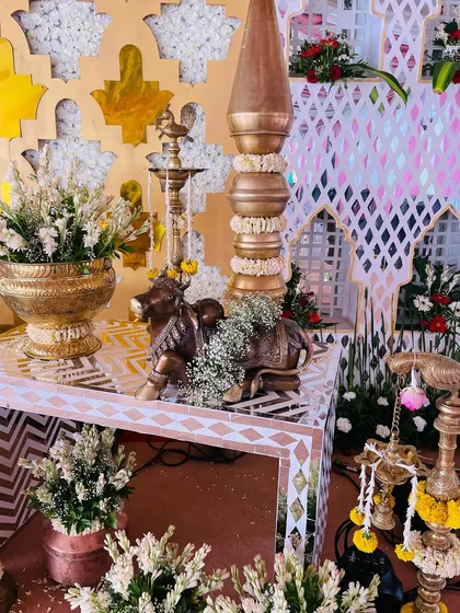 A close-up of the intricate props used in a South Indian themed baby shower, including a mirrored table, brass cow statue, and traditional lamps.