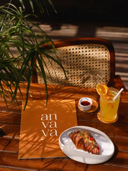 A quiet moment at our Pavilion, with our menu, a savory croissant, and a refreshing drink.
