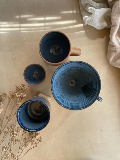 A collection of my handmade ceramic mugs, each with its own unique shape and glaze. The little coffee bean detail on the handle is a fun touch for coffee lovers.