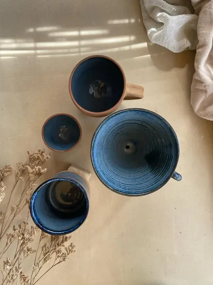 A collection of my handmade ceramic mugs, each with its own unique shape and glaze. The little coffee bean detail on the handle is a fun touch for coffee lovers.