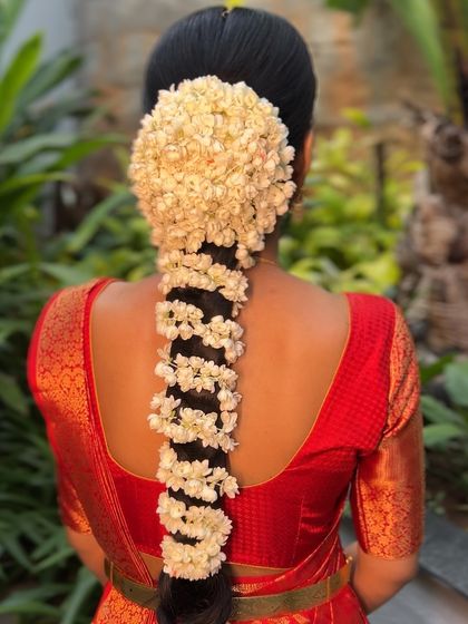 A classic South Indian bridal hairstyle with a full bun of jasmine flowers leading into a traditionally plaited braid, also adorned with jasmine.