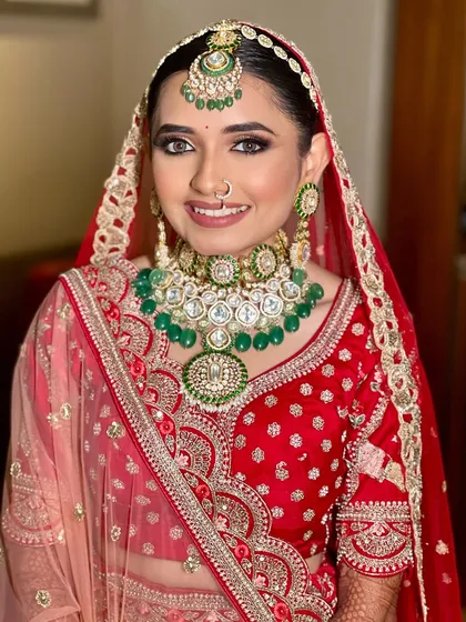 A happy and confident bride, looking directly at the camera. Her makeup is fresh and radiant, enhancing her natural beauty and complementing her traditional attire.