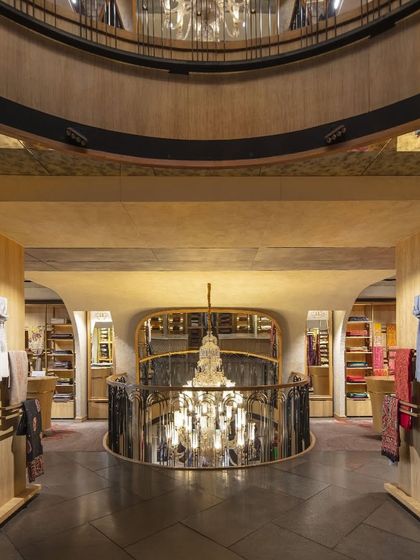 A view from the upper level of Ahujasons shows the grand, open feel of the store. The curved voids and cascading chandeliers create a sense of vertical connection, while mirrors reflect the intricate details and rich textures of the space.