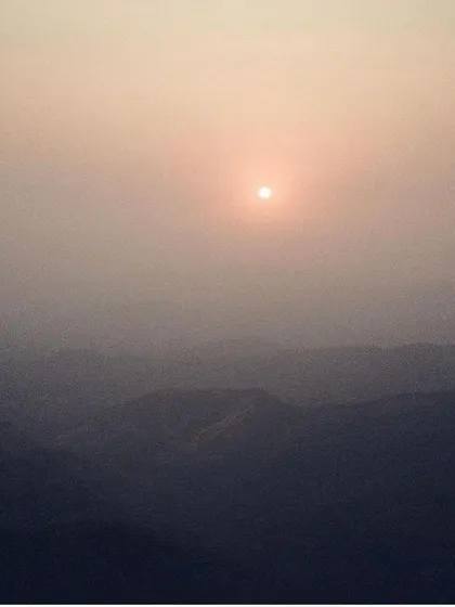 A hazy, mystical sunrise over the rolling hills of Maharashtra. The atmosphere here is thick with spiritual energy, supporting deep practice and contemplation.