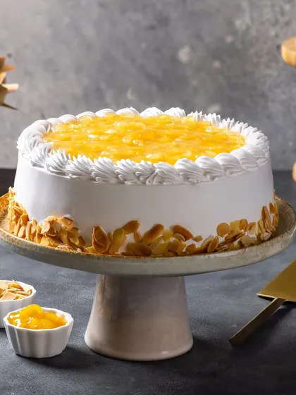 A pineapple cake for Ferns N Petals Luxe, decorated with toasted almond flakes. The styling is clean and elegant, suitable for a premium gifting brand.