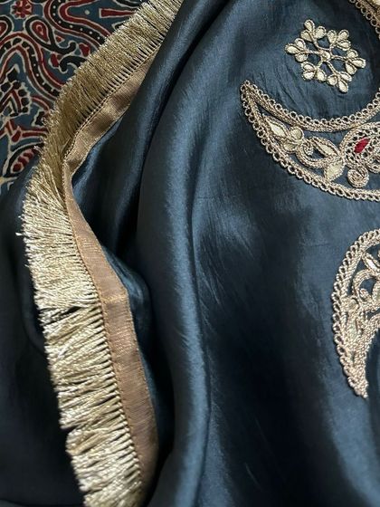 This image focuses on the beautiful embroidered motifs on the Italian silk organza dupatta, featuring crescent moons and stars, set against the fringed gold border.