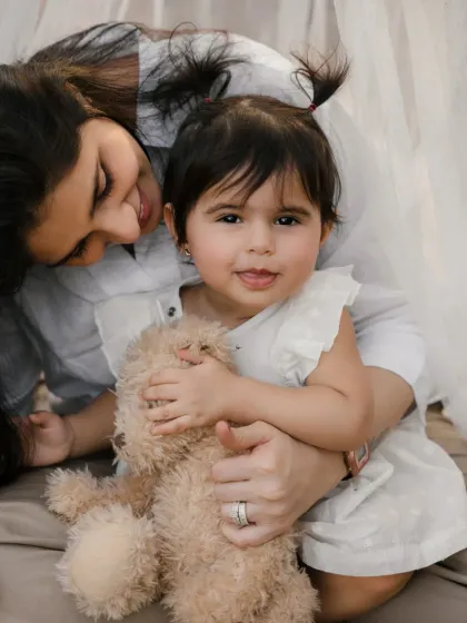 A mother and daughter share a hug inside their whimsical teepee. A lovely portrait from a mother-daughter photoshoot.