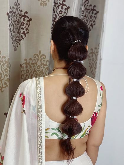 A soft bubble braid wrapped with pearls. This is a modern and chic take on a traditional braid, perfect for a Sangeet or cocktail party.