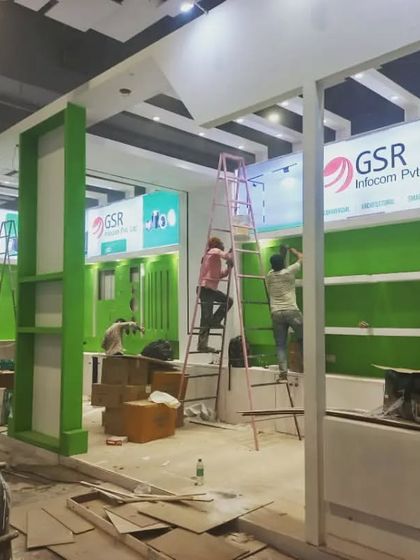 The GSR Infocom booth is being assembled, with its signature green branding and display panels being installed.
