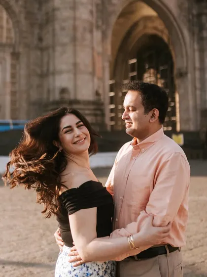A candid moment of affection in front of a historic Mumbai landmark. The gentle breeze catching her hair adds a touch of spontaneous beauty to this engagement portrait.