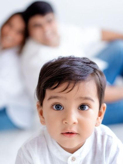 A creative family portrait with the baby in sharp focus in the foreground and the parents softly blurred in the back.