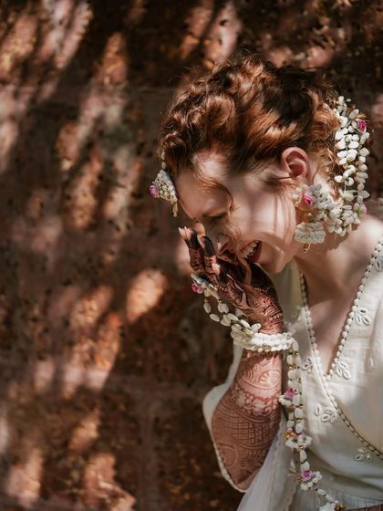 A candid shot capturing the bride's laughter during the ceremony. Even in a moment of pure fun, her chic ivory outfit and floral jewelry look perfectly put together.