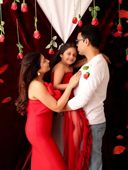 An interactive and loving moment from a Valentine's family shoot. The family shares a tender moment amidst a shower of rose petals, creating a beautiful memory.