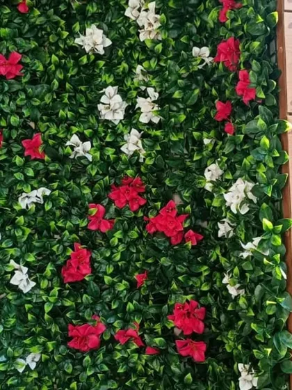 A close-up shot of the floral green wall next to a wooden pillar. The vibrant flowers stand out against the lush green leaves.