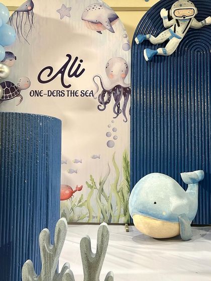 A close-up of the 'One-ders the Sea' theme, showing the detailed whale and coral props against a textured blue backdrop. We love adding these small touches to make a theme feel complete.